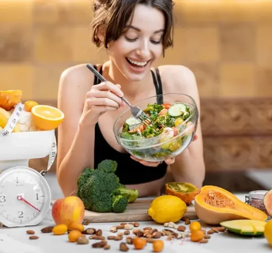 A woman eating a fresh salad, the everyday eating this gummy is meant to sit alongside