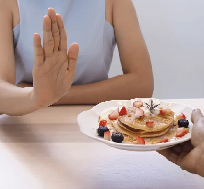A hand refusing a plate of pancakes during an afternoon sugar craving
